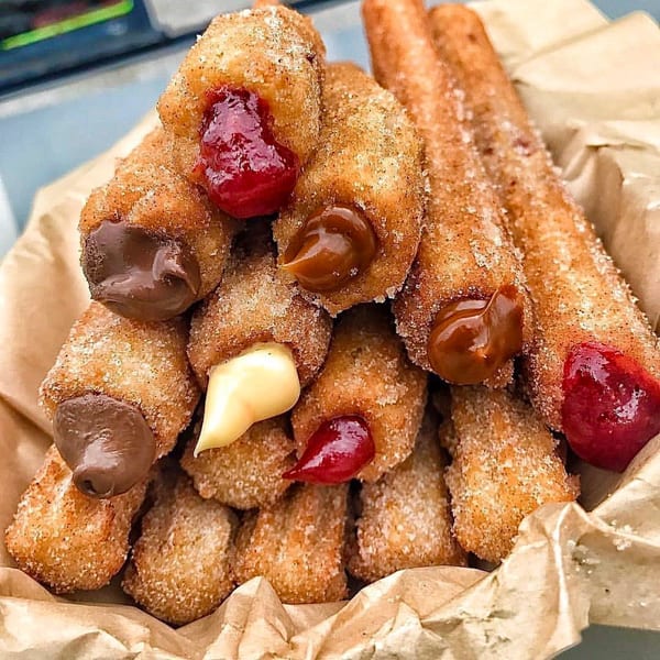 A pile of Churrito Loco churros, some filled with chocolate, caramel, and strawberry jam.