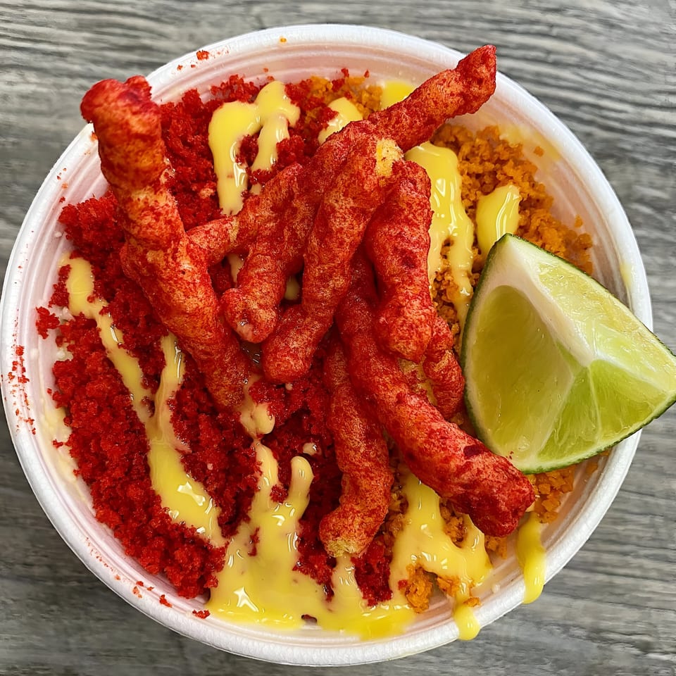 A Churrito Loco dessert with red churritos, yellow sauce, and a lime wedge in a white bowl.