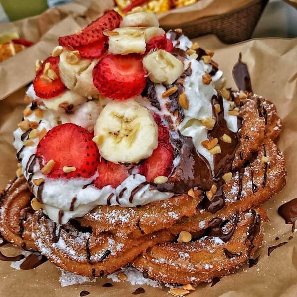 Churrito Loco dessert with churros, whipped cream, strawberries, bananas, chocolate drizzle, and nuts.