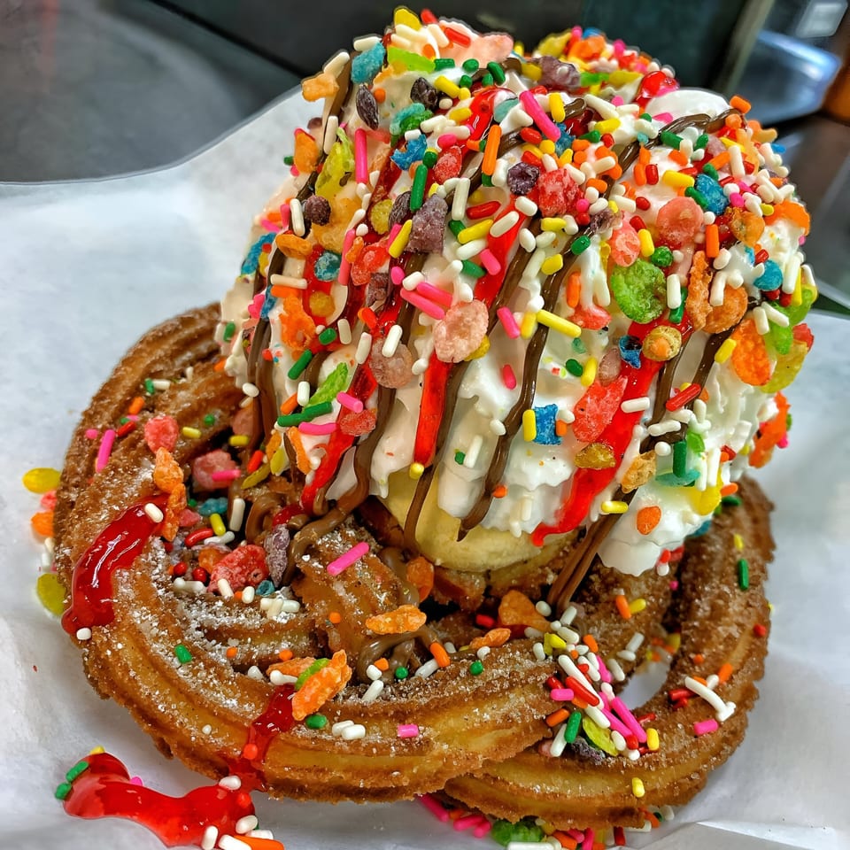 Churrito Loco's churro sundae with ice cream, whipped cream, chocolate, strawberry syrup, and colorful sprinkles.